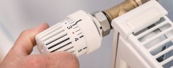 Hand regelt Temperatur an Thermostat der Heizung