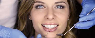 Lächelnde Patientin im Close-up auf Zahnarztstuhl während der Behandlung