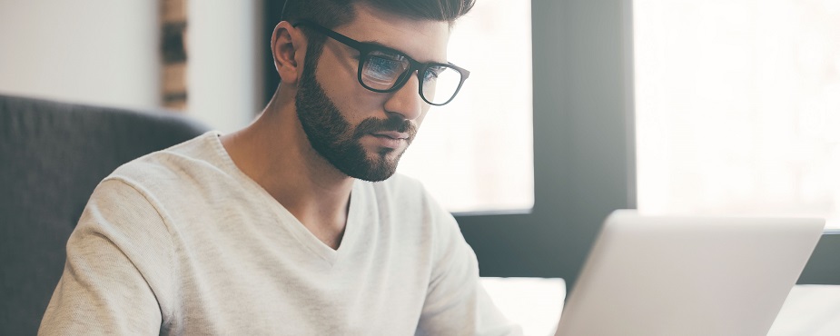 Junger Mann mit Brille vor einem Laptop